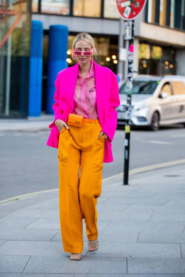 Blazer feminino rosa shock em contraste à calça laranja mostarda